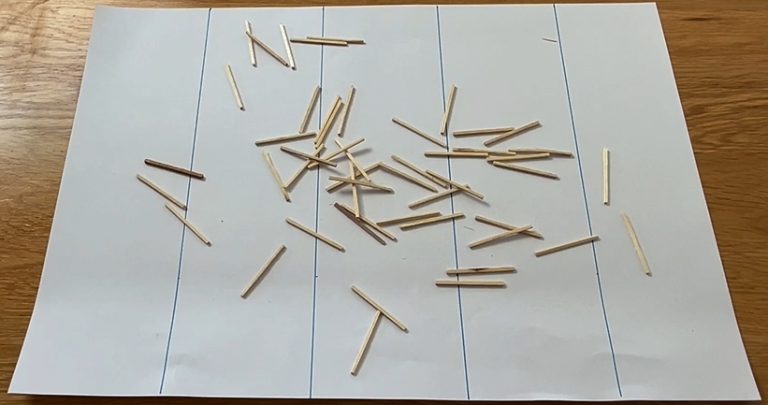 A photo of a sheet of paper with equally spaced lines marked on it. A number of matchsticks have been dropped on the paper.